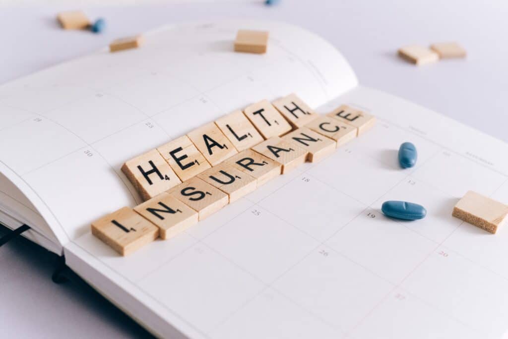 The photo features a calendar with letters from the board game Scrabble, which spell out "Health Insurance". The image will be used for an article about insurance fraud investigations in Florida.